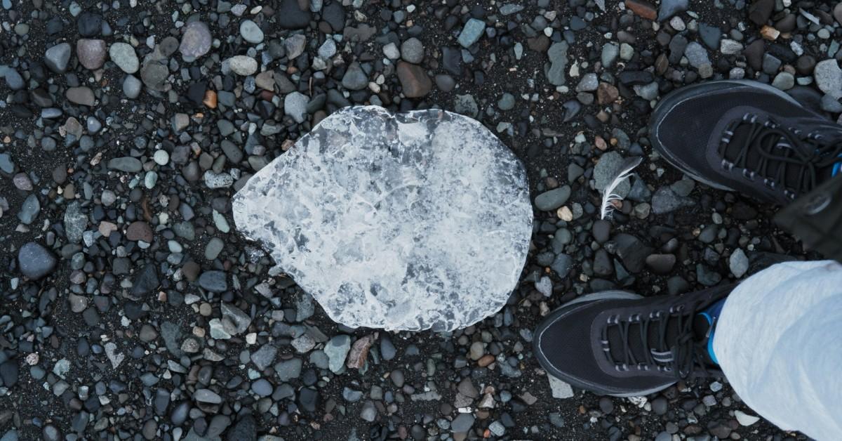 Giant hail stone sitting on some loose rocks with a pair of sneakers for scale